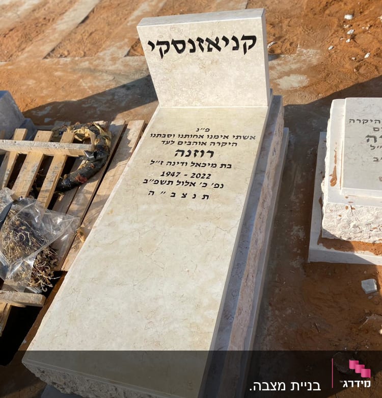 מצבה עם כיתוב בעברית על רקע אדמה